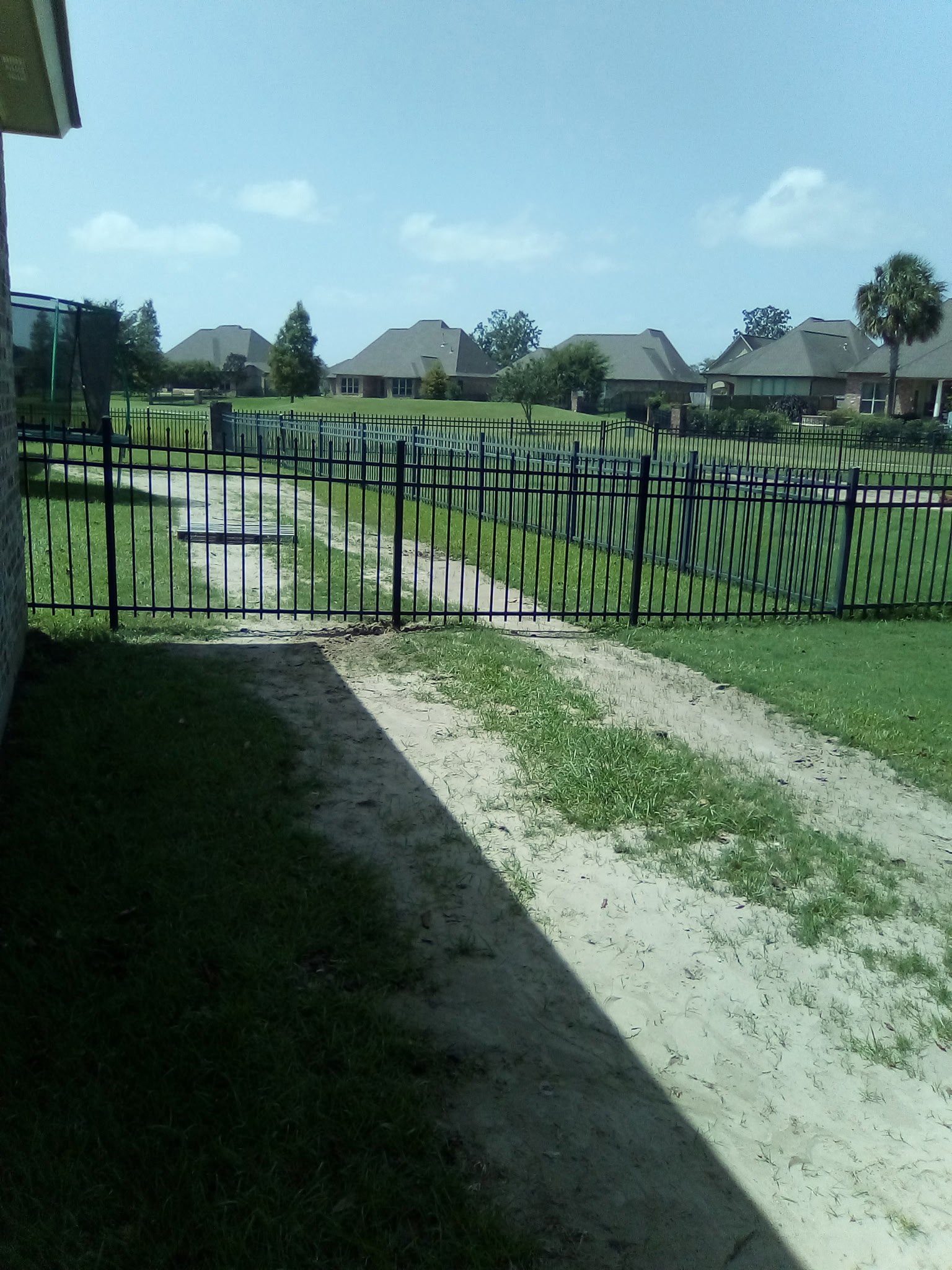 Black ornamental aluminum fence and gate running along a Louisiana subdivision walkway