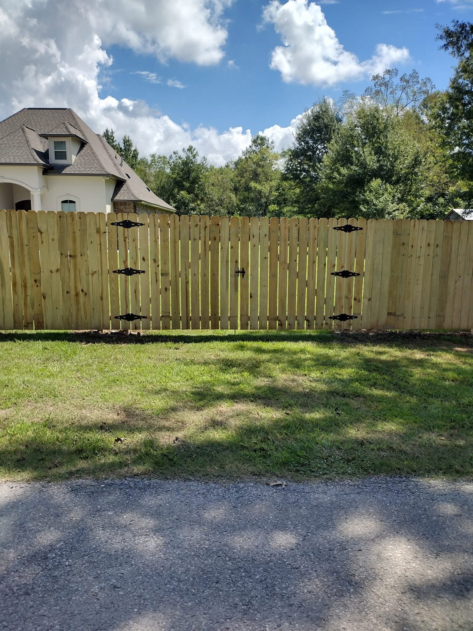 Dog ear wood privacy fence and gate finished with decorative black hinge straps
