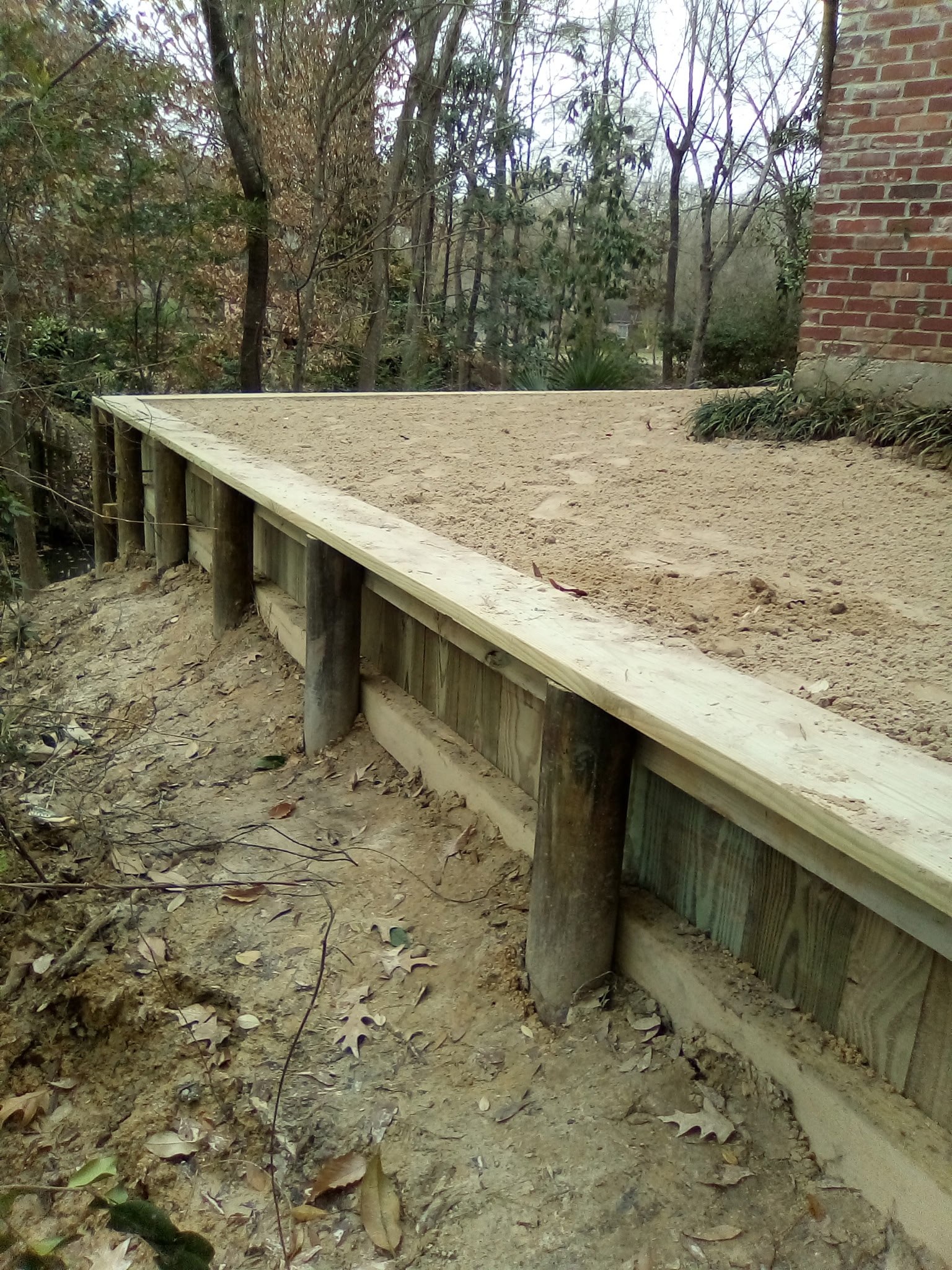 Long timber retaining wall controlling erosion along the side of a Baton Rouge home