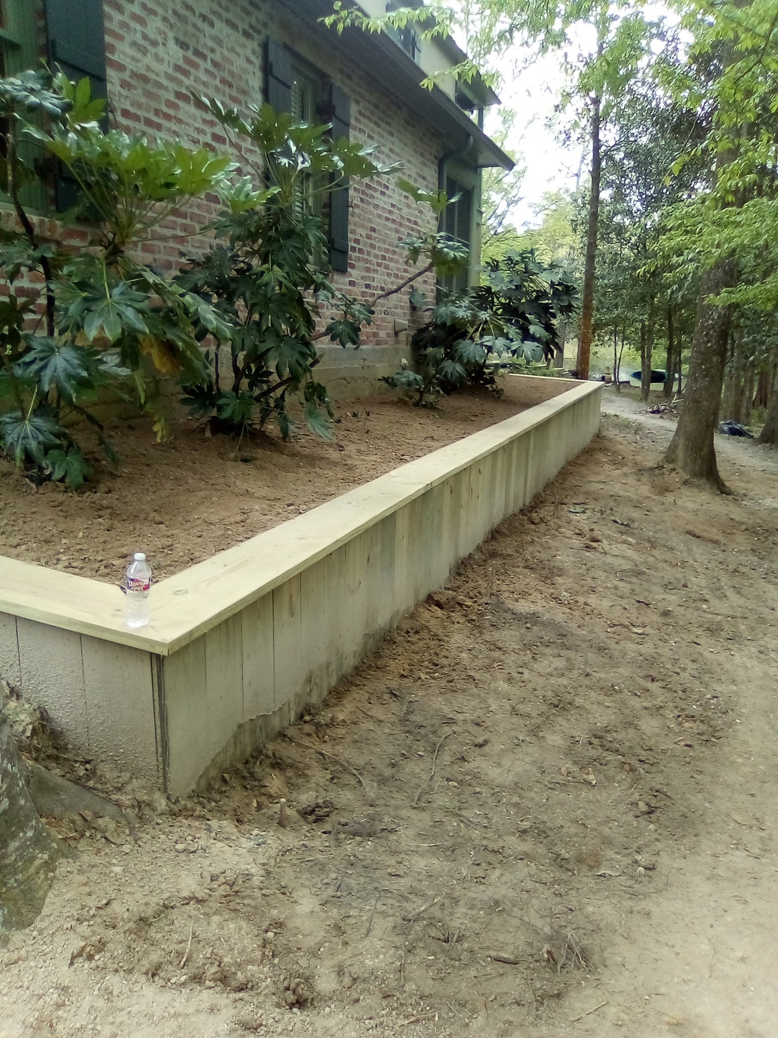 Treated timber retaining wall leveling a planting bed along the side of a Louisiana home