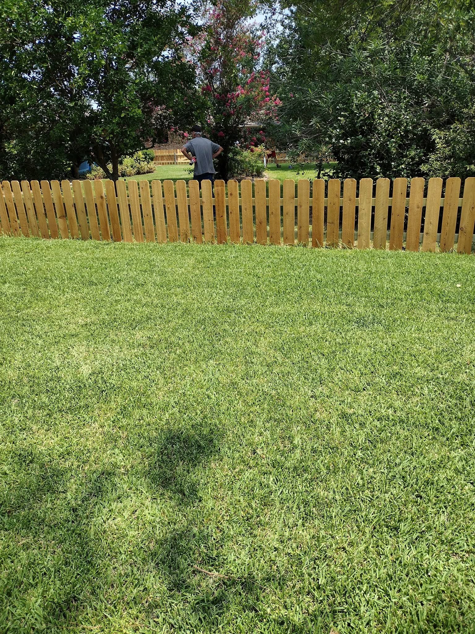 Newly installed wood picket fence lining a large residential backyard in Louisiana