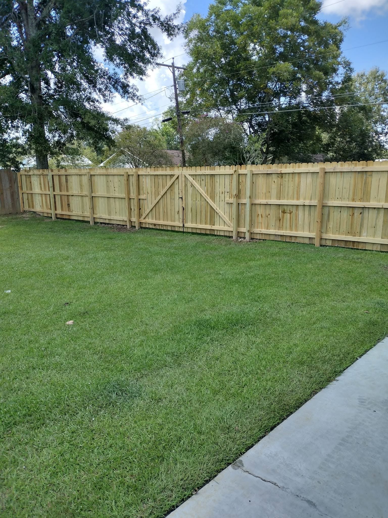 Wood privacy fence with a double walk gate enclosing a Baton Rouge backyard